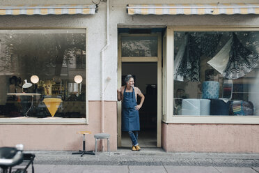 Full length of male upholstery worker looking away while standing at workshop entrance - MASF10596