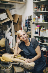Porträt einer selbstbewussten Polsterin, die an einer Werkbank in einer Werkstatt sitzt - MASF10622