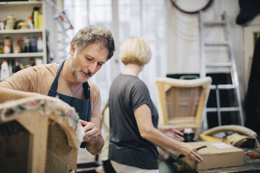 Älterer Handwerker näht ein Sofa in der Werkstatt - MASF10639