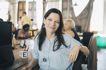 Portrait of confident businesswoman sitting at desk in creative office - MASF10657