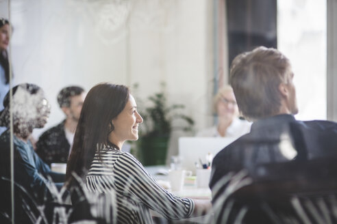 Lächelnde Geschäftsleute, die während einer Brainstorming-Sitzung im Sitzungssaal zuhören - MASF10734
