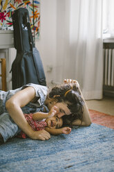 Mutter küsst Tochter auf Teppich liegend zu Hause - MASF10811