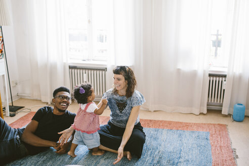 Glückliche Mutter und Vater mit Tochter auf Teppich zu Hause - MASF10817
