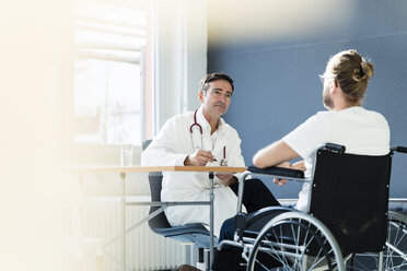 Doctor listening to patient in wheelchair in medical practice - JOSF02780