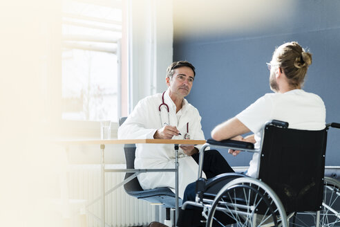 Doctor listening to patient in wheelchair in medical practice - JOSF02780