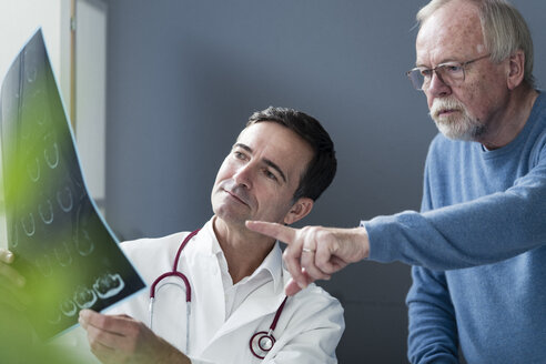 Arzt bespricht MRT-Bild mit älterem Patienten in der Arztpraxis - JOSF02785