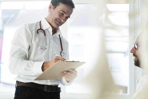 Doctor talking to patient and taking notes in medical practice stock photo
