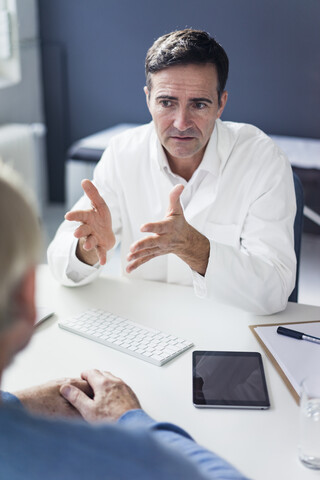 Serious doctor talking to patient in medical practice stock photo