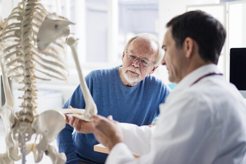 Doctor explaining bones at anatomical model to patient in medical practice - JOSF02809