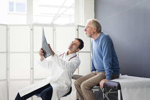 Arzt bespricht MRT-Bild mit Patient in der Arztpraxis, lizenzfreies Stockfoto