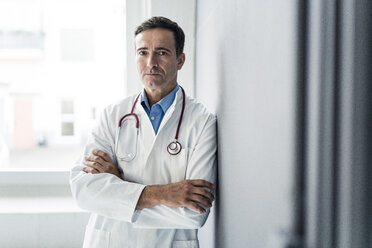 Portrait of serious doctor leaning against a wall - JOSF02816