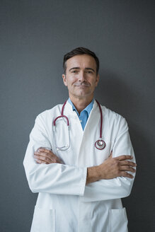 Portrait of confident doctor standing at a grey wall - JOSF02820