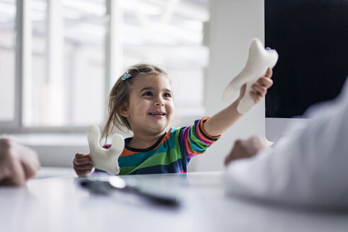Portrait of smiling girl with tooth model at desk in medical practice - JOSF02836