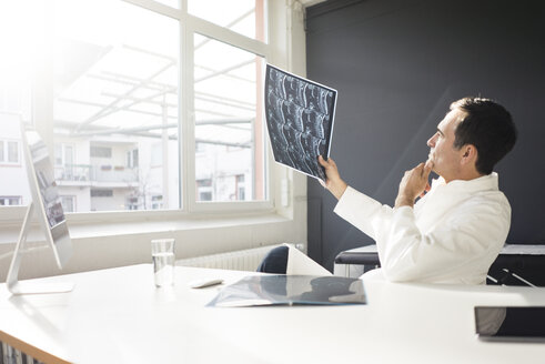 Arzt prüft MRT-Bild am Schreibtisch in einer Arztpraxis - JOSF02838