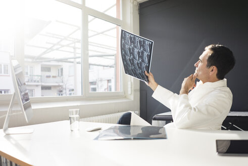 Doctor examining MRT image at desk in medical practice - JOSF02838