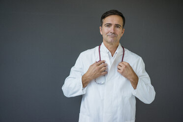 Porträt eines selbstbewussten Arztes vor einer grauen Wand - JOSF02840
