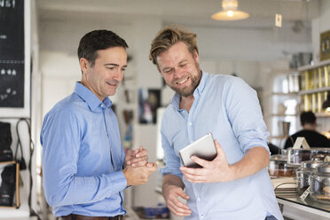Two smiling businessmen sharing tablet - JOSF02847
