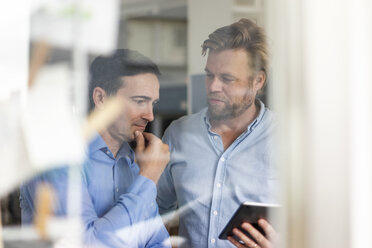 Two businessmen sharing tablet and thinking - JOSF02849