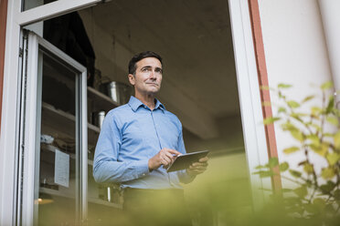 Businessman with tablet at open French door - JOSF02853