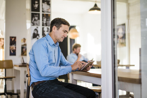 Businessman sitting at table using tablet stock photo