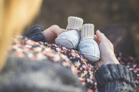 Close-up of pregnant woman holding baby shoes stock photo