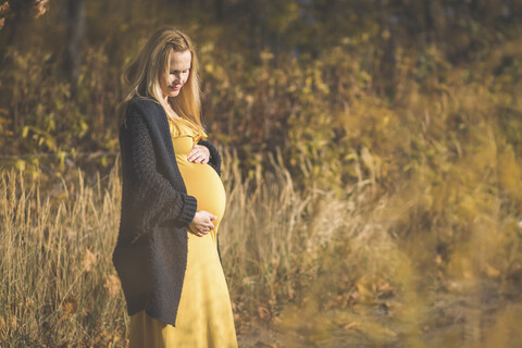 Schwangere Frau auf einem Waldweg im Herbst, lizenzfreies Stockfoto