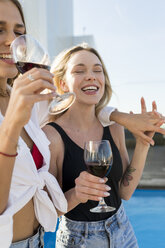 Freundinnen auf einer Dachterrasse, die sich am Pool vergnügen und Rotwein trinken - VABF02110