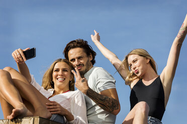Friends having fun on a rooftop terrace, taking selfies - VABF02121