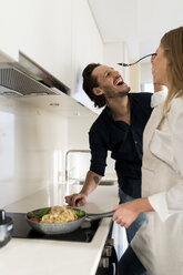 Happy couple preparing spaghetti in their kitchen - VABF02129