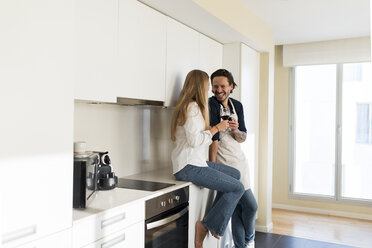 Affectionate couple drinking redwine in the kitchen - VABF02132