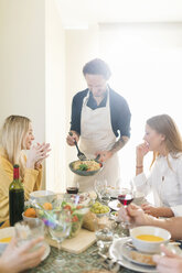 Friends having lunch together, host serving pasta - VABF02137