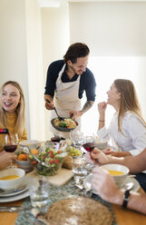 Friends having lunch together, host serving pasta - VABF02138