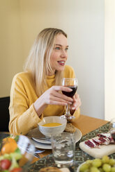 Junge Frau trinkt Rotwein bei einem Mittagessen mit Freunden - VABF02140