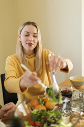 Junge Frau isst Salat bei einem Mittagessen mit Freunden - VABF02148