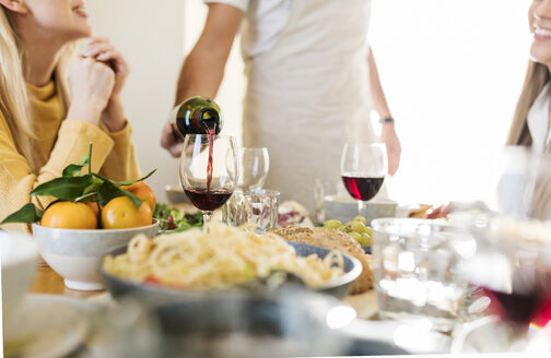 Freunde beim gemeinsamen Mittagessen, Gastgeber schenkt Rotwein ein - VABF02154