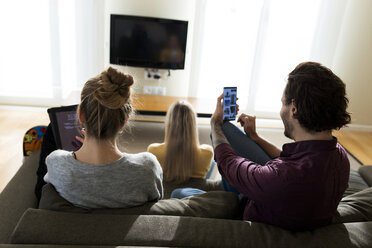 Freunde sitzen auf der Couch im Wohnzimmer und benutzen digitale Geräte - VABF02182