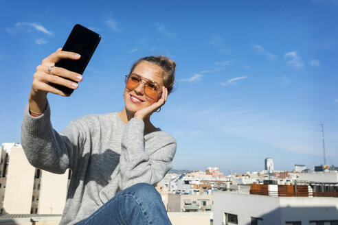 Junge Frau macht Smartphone-Selfies auf einer städtischen Dachterrasse - VABF02199