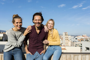 Freunde sitzen auf einer städtischen Dachterrasse, die Arme umeinander gelegt - VABF02201