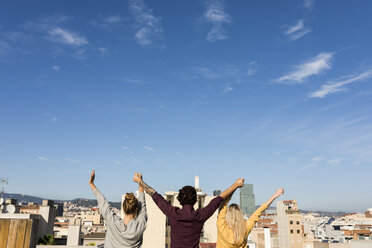 Freunde haben Spaß auf einer städtischen Dachterrasse und heben die Arme - VABF02202