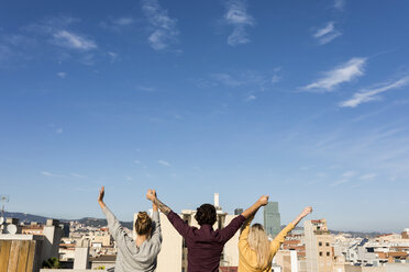 Friends having fun on an urban rooftop terrace, raising arms - VABF02202