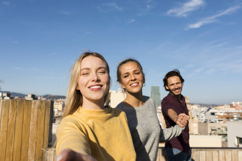 Freunde, die sich auf einer städtischen Dachterrasse amüsieren und die Hände halten - VABF02203