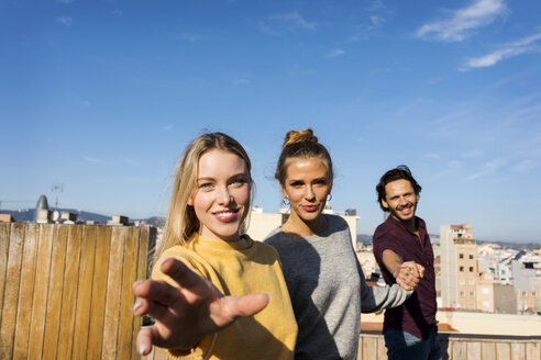 Freunde, die sich auf einer städtischen Dachterrasse amüsieren und die Hände halten - VABF02204