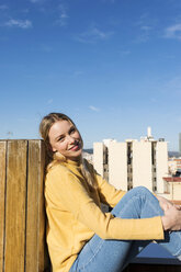 Junge Frau entspannt sich auf einer städtischen Dachterrasse - VABF02206