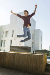 Man on a rooftop terrace, jumping for joy - VABF02220