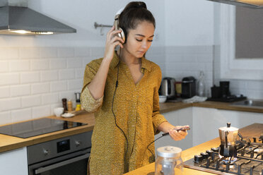 Junge Frau hört Musik in der Küche, während sie ihren Morgenkaffee zubereitet - ERRF00610
