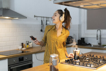 Junge Frau hört Musik in der Küche, während sie ihren Morgenkaffee zubereitet - ERRF00611