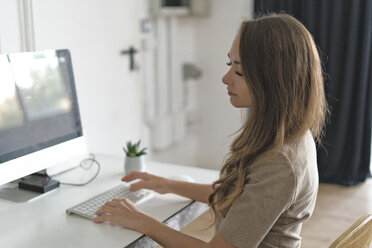 Young woman sitting at her desk, thinking - ERRF00622