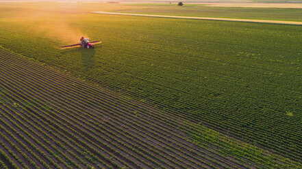 Serbia, Vojvodina, Aerial view of a tractor spraying soybean crops - NOF00076