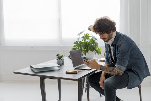 Mann arbeitet in einem Coworking Space und benutzt ein Smartphone - AFVF02223