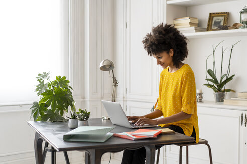 Woman sitting at desk, working, using laptop - AFVF02247